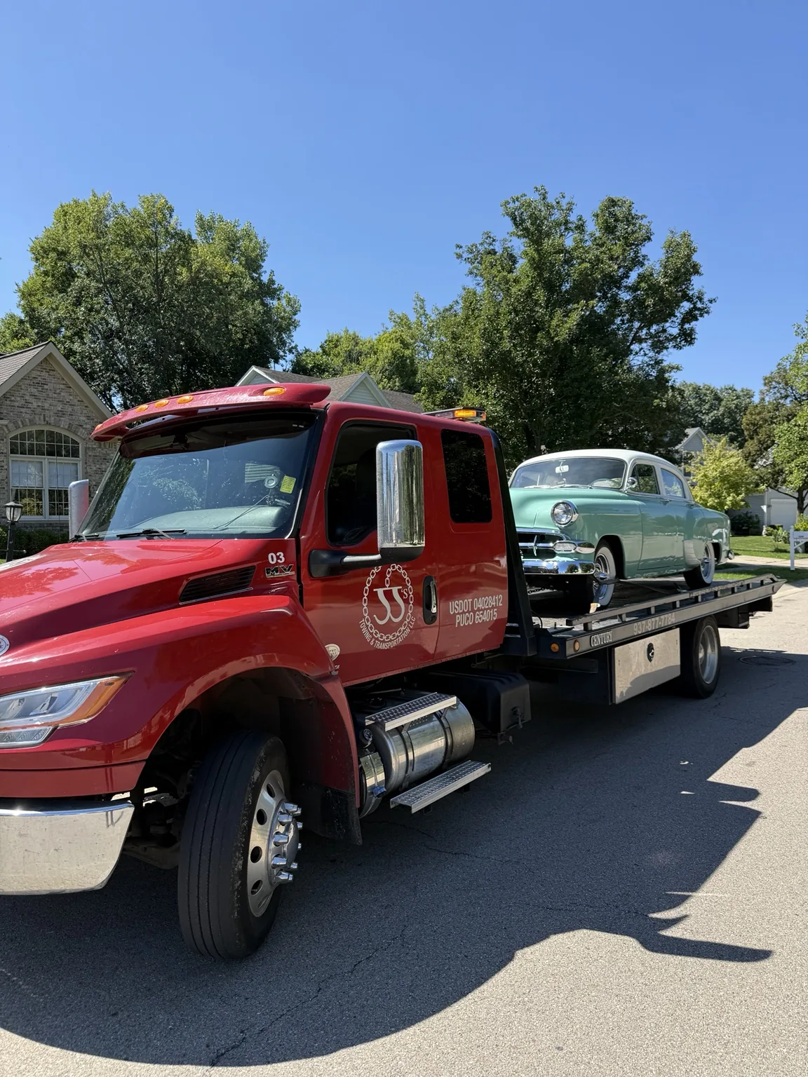 JJ’s red flatbed towing a passenger car